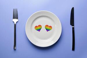 due cuori nei colori della bandiera lgbt nel piatto. incontri romantici della comunità gay. cena senza discriminazioni contro le minoranze sessuali. Preparazione del banchetto di nozze lgbt. foto