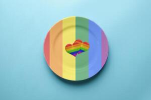 due cuori nei colori della bandiera lgbt nel piatto. incontri romantici della comunità gay. cena senza discriminazioni contro le minoranze sessuali. Preparazione del banchetto di nozze lgbt. foto