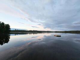 nuoto isola nel Svezia su un' lago a tramonto. nuvole riflessa nel il acqua. foto