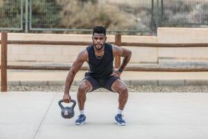 atletico nero uomo occupazione con kettlebell nel parco foto