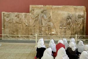 Teheran, Iran, 2016 - ragazze della scuola in hijab bianco che frequentano la lezione di storia davanti al bassorilievo di persepoli del re Dario al museo nazionale. foto