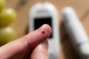 donna pungere sua dito per dai un'occhiata sangue glucosio livello con glucometro, test sangue glucosio per diabete foto