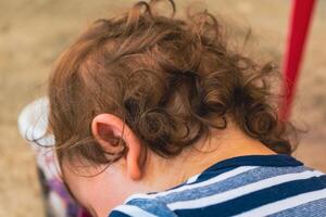 indietro Visualizza di il testa di un' bambino con leggermente Riccio leggero Marrone capelli foto