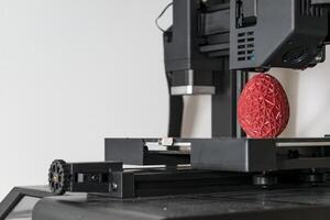 vicino su di un' 3d stampante stampa un' rosso poligonale uovo foto