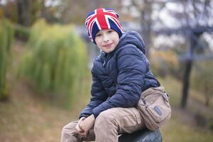 un' contento bambino nel un' Britannico bandiera cappello sembra a il telecamera. foto