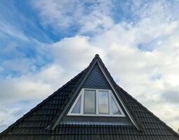 finestra da tetto aperta in stile velux con tegole nere. foto