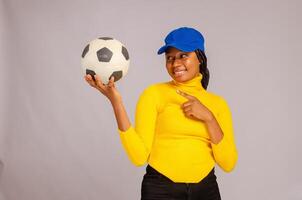 bellissimo africano signora sorridente come lei punti per il palla su sua mano foto