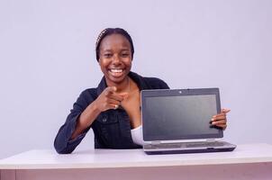 ritratto di un' bellissimo giovane nero donna mostrando sua il computer portatile schermo foto