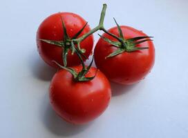 tre totale pomodori nel un' ramo su bianca plastica taglio tavola foto