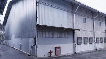 industriale edificio con acciaio tetto costruzione e installato scarico fan su il parete, e con idrante installazione. foto