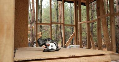 circolare sega nel un' di legno Casa sotto costruzione. costruzione di un' nuovo di legno Casa utilizzando telaio tecnologia. carpenteria e costruzione concetto. foto