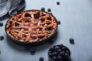 rosso frutta e mirtillo torta presentata su un' leggero blu sfondo. foto