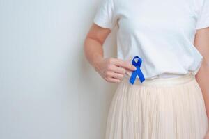 donna Tenere blu nastro con avendo addome dolore. marzo colorettale cancro consapevolezza mese, colonico patologia, grande intestino, ulcerosa colite, digestivo sistema e Salute concetto foto