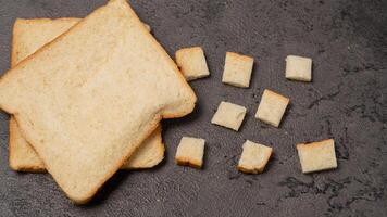 affettato pane isolato su grigio sfondo. pane tagliare in piccolo piazze foto