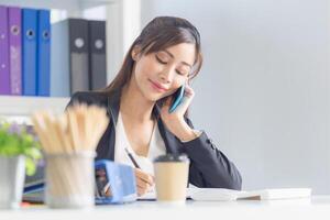 ritratto di giovane attività commerciale donna manager Lavorando a il ufficio, asiatico donna utilizzando smartphone nel ufficio foto