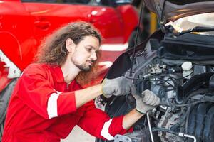 meccanico uomo Lavorando nel box auto, giovane meccanico fissaggio auto nel auto riparazione negozio foto