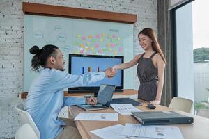 uomini d'affari di etnia asiatica si stringono la mano per affrontare partnership commerciali e lavorare insieme dopo che una bellissima giovane manager donna ha presentato un grafico di successo nella sala riunioni dell'ufficio. foto