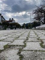 pietra pavimentazione pietre allungamento in il distanza lungo il case contro il sfondo di Basso nuvole foto