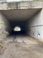 un vecchio tunnel sotto il strada a il altro fine voi può vedere il sole foto