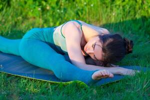 bellissimo giovane donna fare allungamento esercizio su verde erba nel un' campo o un' parco. foto