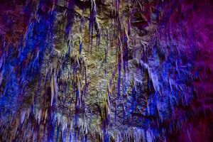 carsico grotta, sorprendente Visualizza di stalattiti e stalagmiti nel colorato luminosa luce, bellissimo naturale punto di riferimento nel turistico posto. foto