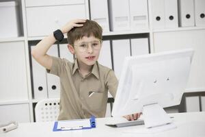 un' bambino con bicchieri a il computer. scolaro imparare per il tenere sotto controllo. un idea è venuto per mente foto