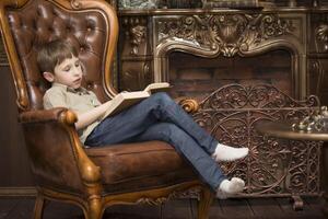 il bambino nel il sedia lettura un' libro.piccolo ragazzo con un' libro foto