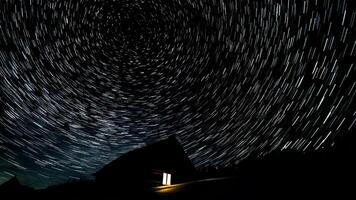 di legno Casa nel il montagne nel inverno. stella sentieri nel il notte cielo. foto