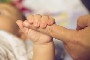 il mani di il madre hold il del bambino mano con amore e premuroso. foto