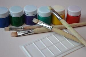 dipingere spazzole e un' riga di chiuso barattoli di colorato guazzo vernici. impostato per creatività e passatempo. foto