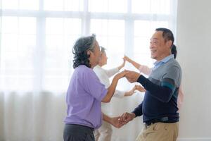 asiatico più vecchio maschio e femmine persone danza con loro partner su un' danza pavimento nel vivente spazio. contento più vecchio coppia l'esecuzione ottenere esercizio. gioioso spensierato pensionato anziano amici godendo rilassamento foto