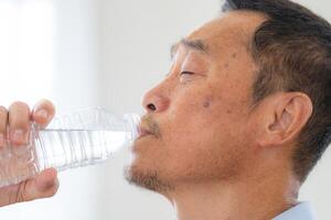 felicità di maschio anziano Tenere un' bottiglia di acqua. anziano persone potabile fresco minerale acqua. foto