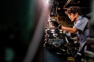 asiatico lavoratore nel produzione pianta perforazione a macchina. professionale lavoratore vicino perforazione macchina su fabbrica. finitura metallo Lavorando interno acciaio superficie su tornio macinino macchina con volante scintille. foto