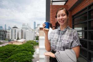 africano attività commerciale inteligente donna sta a all'aperto terrazza costruzione. persone con su mano nel bene sensazione con città spazio costruzione. rilassante di persone attività commerciale mattina. foto