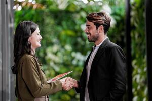 uomo d'affari e casuale donna d'affari tremante mani all'aperto. Due giovane multiculturale collaboratori affare per successo. sfondo di verde parete natura alberi. foto