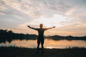 indietro Visualizza silhouette di un' corridore uomo in esecuzione su il spiaggia a tramonto con sole nel il sfondo foto