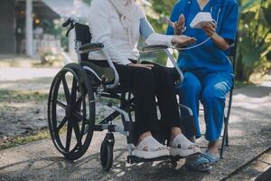 infermiera con anziano uomo nel sedia a rotelle a parco foto