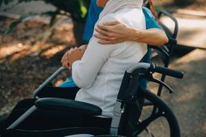 un' infermiera prendere cura un' anziano maschio su sedia a rotelle nel il suo giardino a casa foto