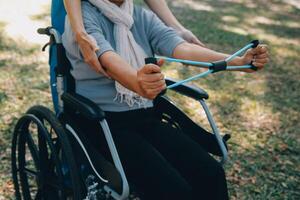 giovane infermiera o fisioterapista nel scrub porzione un' contento pensionato vecchio donna fare fitness esercizi con leggero peso manubri a casa. concetto di fisioterapia per gli anziani foto