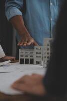 costruzione e struttura concetto di ingegnere o architetto incontro per progetto Lavorando con compagno e ingegneria utensili su modello edificio e planimetria nel Lavorando luogo, contrarre per tutti e due aziende. foto