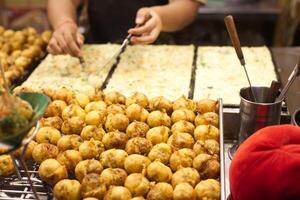 capocuoco cucinando takoyaki servire per vendere nel tailandese notte strada mercato foto