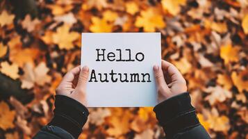 ai generato Ciao autunno. uomo Tenere carta con Ciao autunno lettering su giallo le foglie sfondo. foto