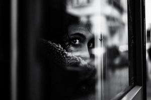 ai generato nero e bianca ritratto di un' giovane donna guardare su il finestra. foto