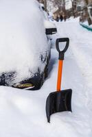 plastica neve pala nel davanti di innevato auto a inverno mattina foto