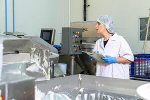 caucasion donna Lavorando nel un' cibo fabbrica indossare protettivo Abiti e guanti. foto