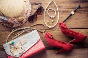 Accessori per adolescenziale ragazza su sua vacanza, cappello, elegante per estate occhiali da sole, pelle Borsa, scarpe e costume su di legno pavimento. foto