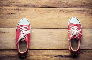 rosso scarpe da ginnastica, mettere su il legna pavimento. foto