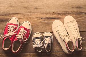 tre coppie di scarpe posare su il di legno pavimento di il famiglia, genitori e bambini per fare insieme. foto