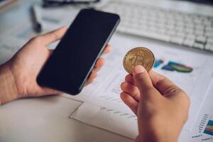 uomo Tenere bitcoin e sfondo con inteligente telefoni, computer portatili e attività commerciale grafici - concetti per di partenza un' attività commerciale e investire foto