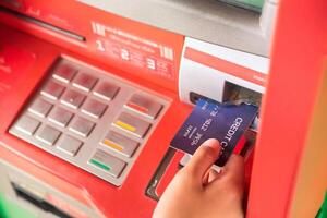 mano inserzione con un' credito carta in banca macchina . uomo utilizzando un ATM macchina con credito carta per ritirarsi i soldi foto